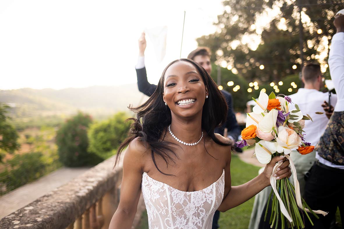 Novia sonriente con ramo de flores en su boda al aire libre en Mallorca, reflejando alegría y planificación perfecta