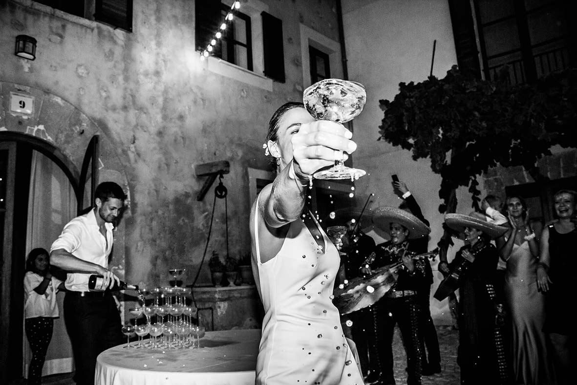 Bride celebrating with champagne at wedding reception in Mallorca, captured by destination wedding photographer.