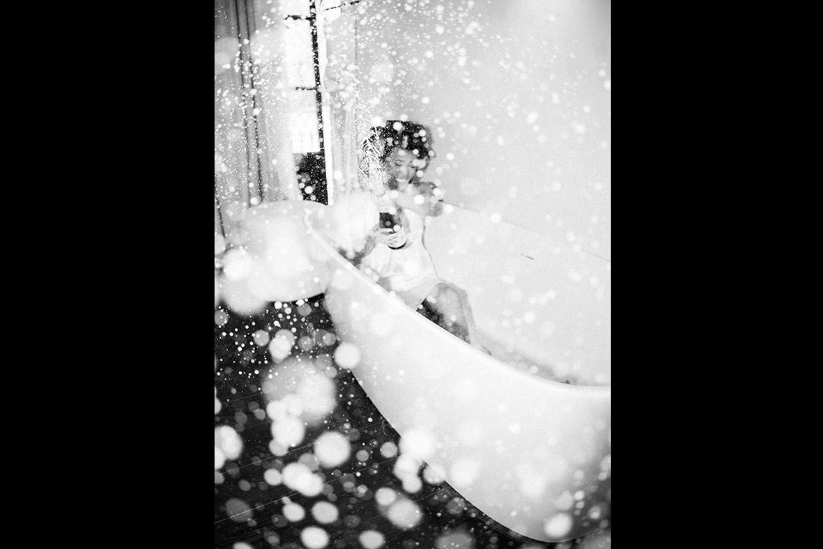 Artistic black and white photo of bride celebrating with champagne in a bathtub, captured by luxury wedding photographer in Mallorca.