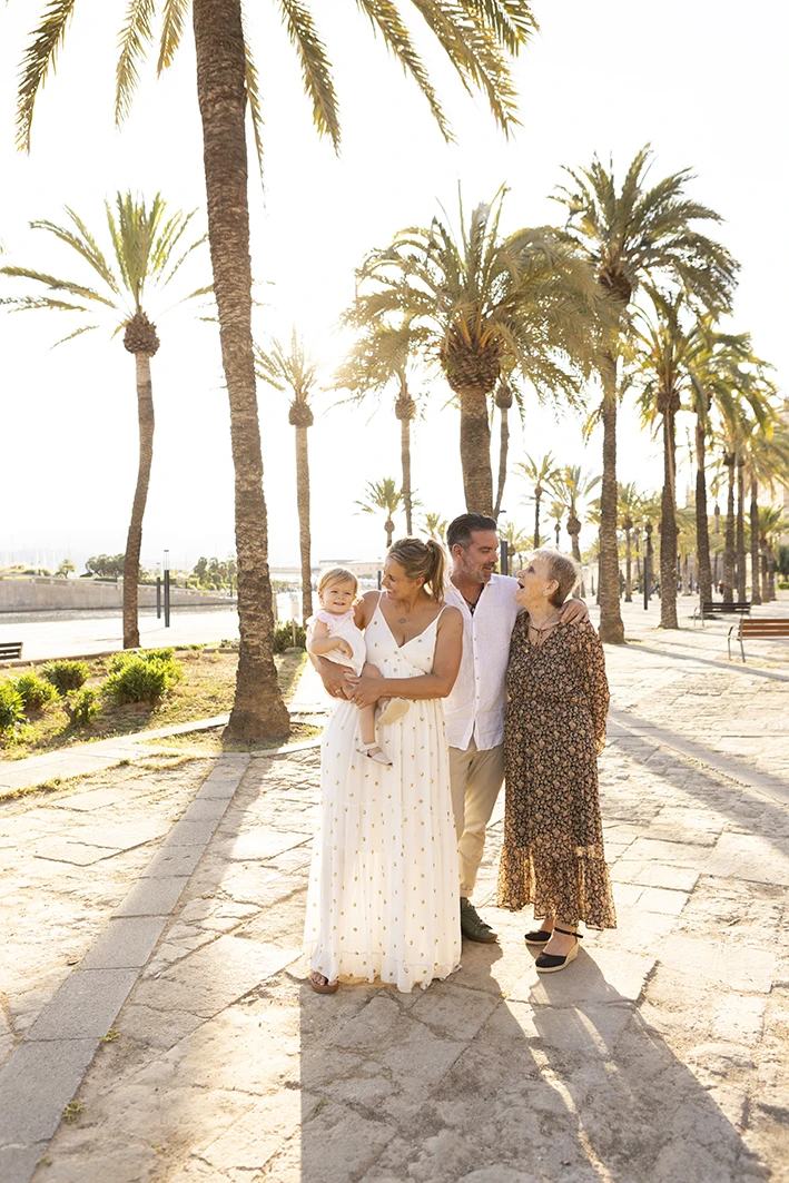 Familia posando bajo palmeras durante una sesión de fotografía familiar en Mallorca