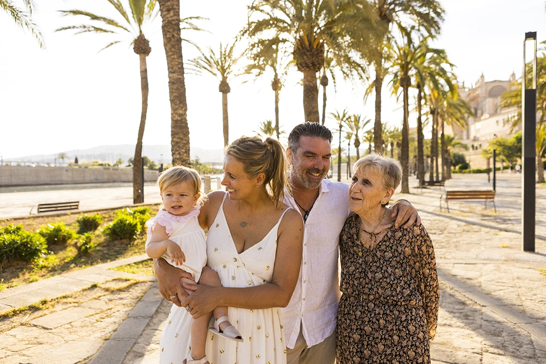 Familia sonriente caminando entre palmeras durante una sesión de fotografía familiar en Mallorca