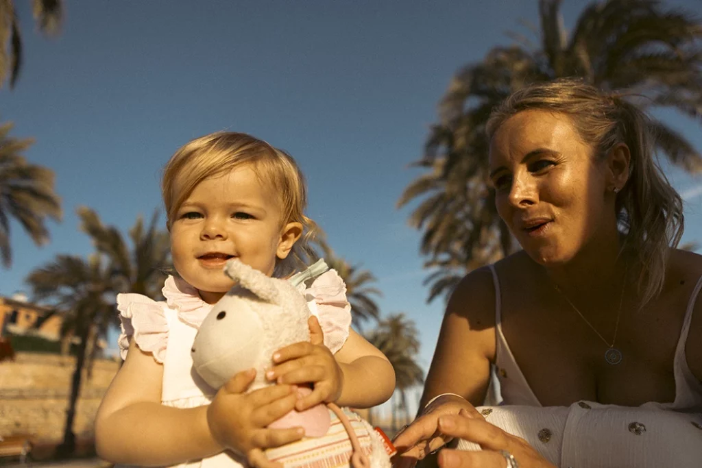 Niña con su peluche junto a su madre durante una sesión de fotografía familiar en Mallorca