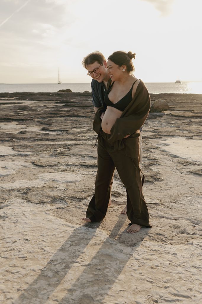 Pareja esperando a su bebé durante una sesión de fotos en la playa de Mallorca