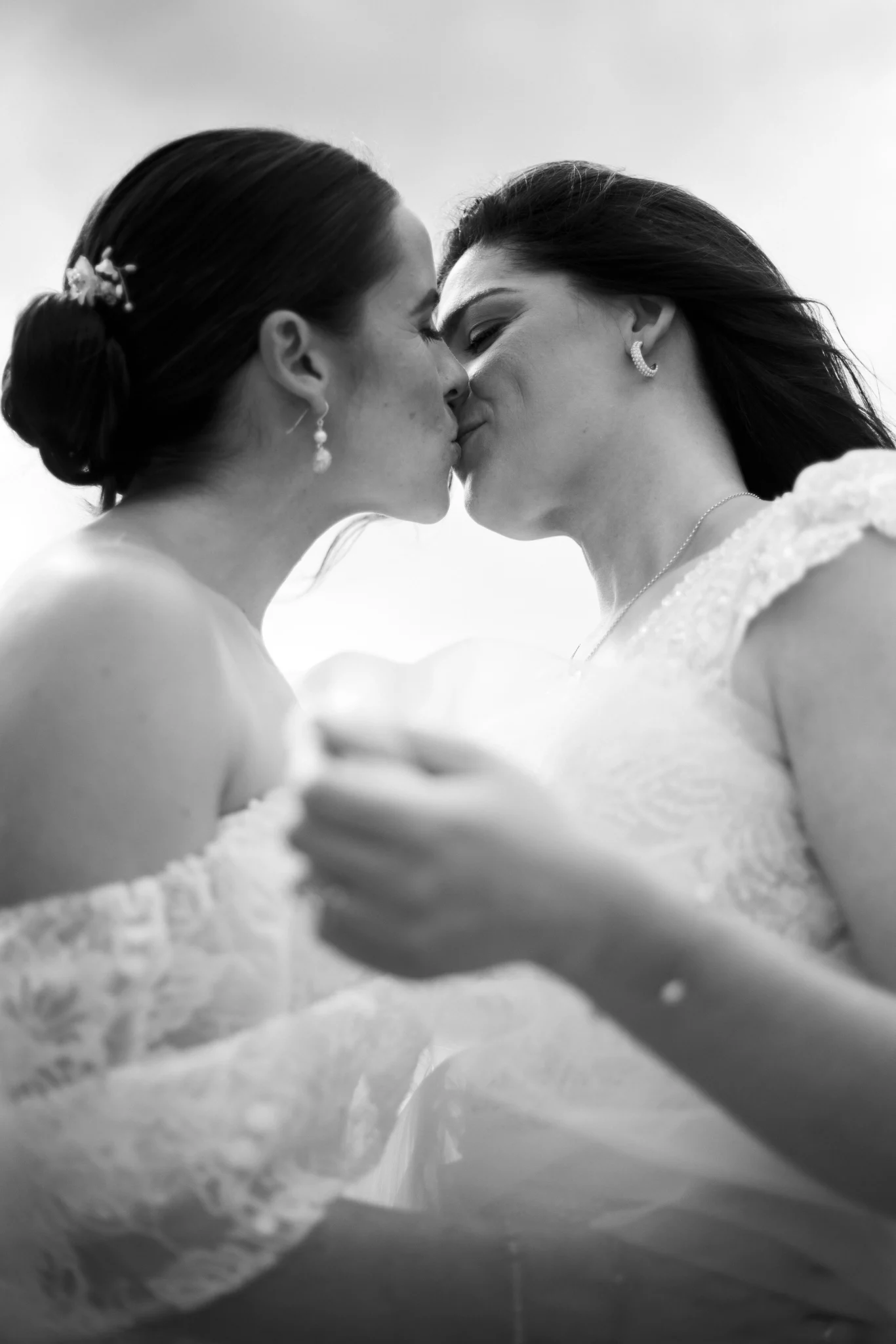 Close-up of two brides kissing on their wedding day – black and white photo by Inma del Valle