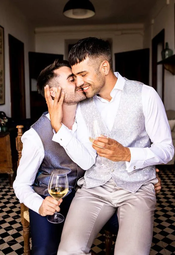 Two grooms sharing a kiss and wine before the wedding – photo by Inma del Valle