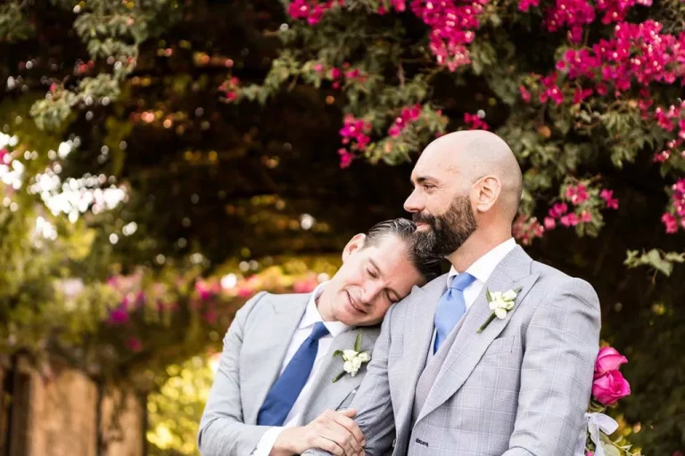 Groom resting his head on his partner’s shoulder during an outdoor wedding – photo by Inma del Valle