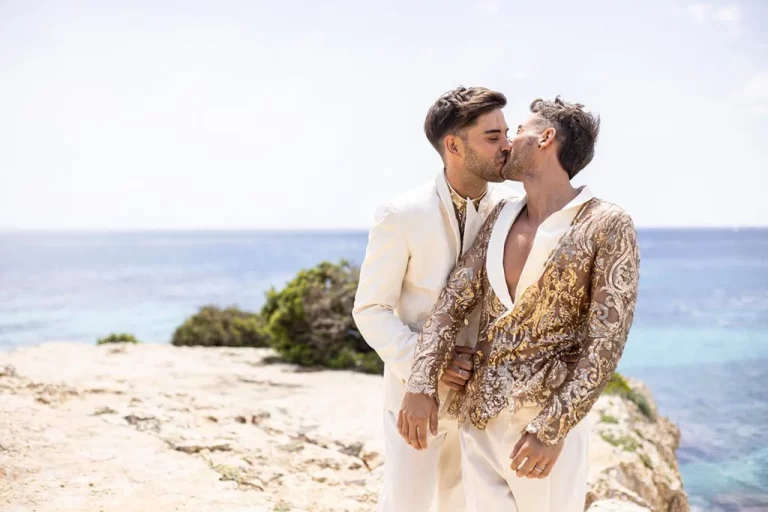 Two grooms kissing on a Mediterranean beach with ocean view – photo by Inma del Valle
