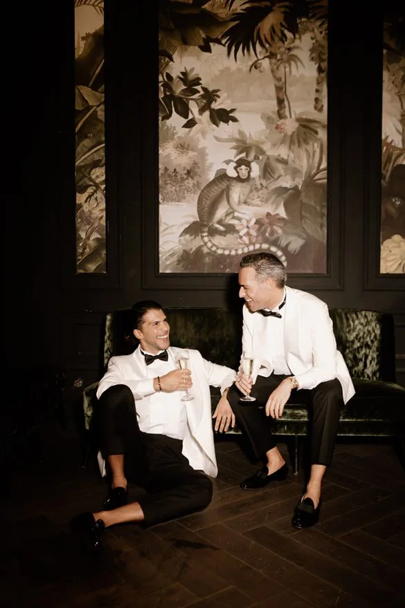 Pareja gay relajándose tras su boda de lujo en Mallorca, vestidos con esmoquin blanco, fotografía de Inma del Valle.