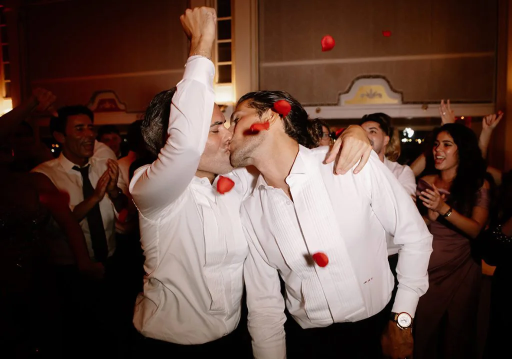Pareja gay besándose entre pétalos de rosa en su boda de lujo en Mallorca, en plena celebración, captada por Inma del Valle.