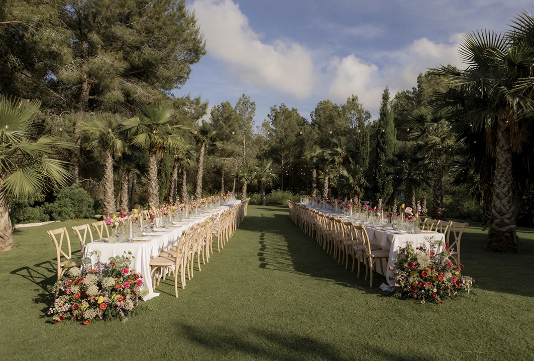 Outdoor reception setup with long tables and floral arrangements at a luxury wedding in Sitges.