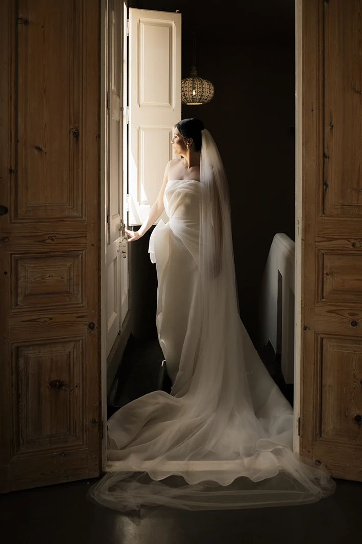 Bride in wedding dress gazing out the window before her luxury wedding in Sitges.