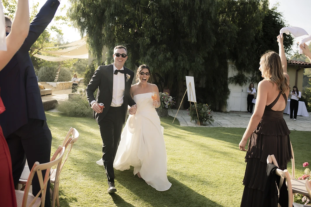 Bride and groom joyfully entering their luxury wedding in Sitges.