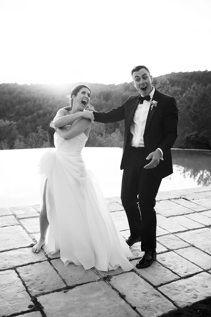Bride and groom laughing and dancing by the pool during their wedding in Sitges.