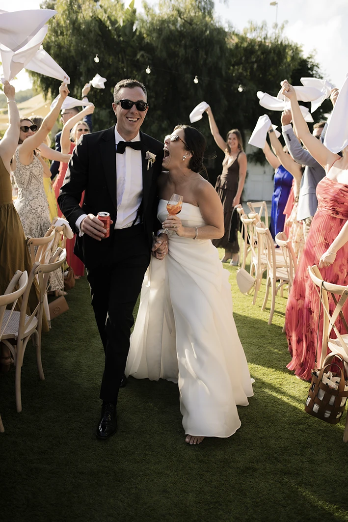 Newlyweds Kendal and Matt walk through cheering guests at their luxury wedding in Sitges.
