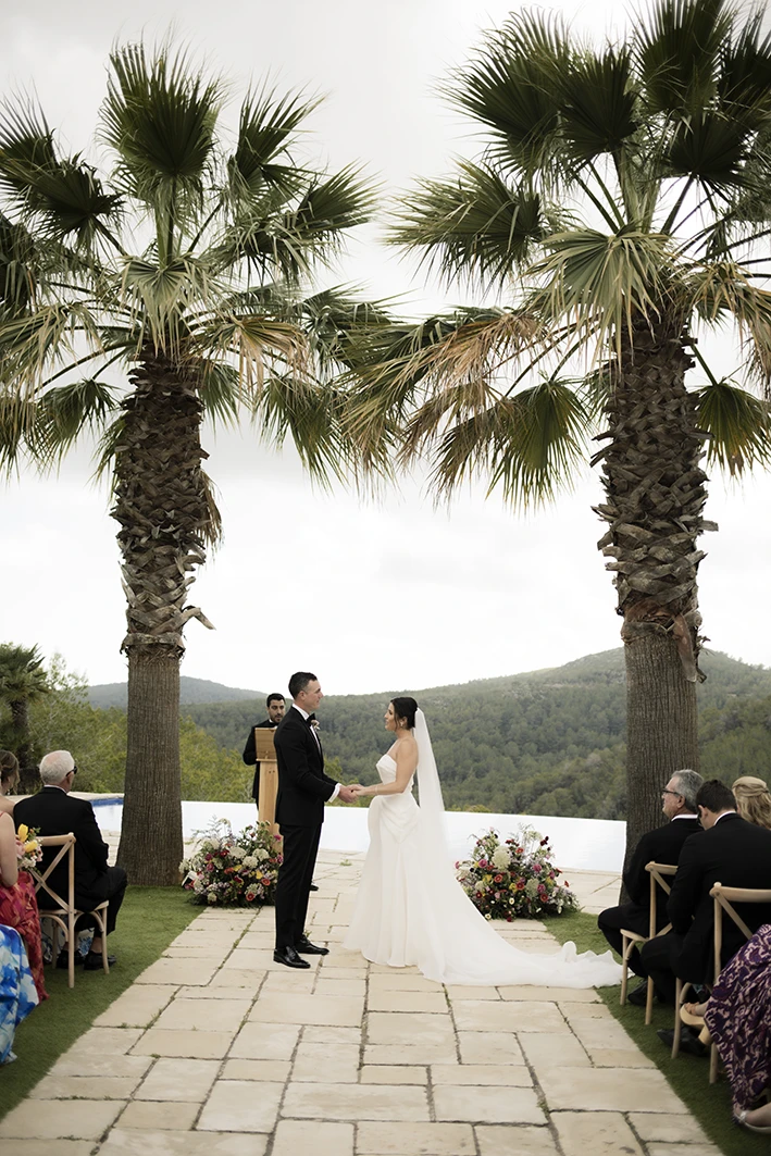 Bride and groom holding hands under palm trees at a luxury wedding in Sitges.