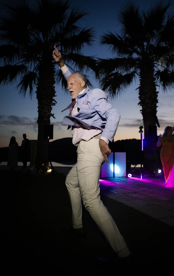 Wedding guest dancing energetically under the palm trees during a luxury wedding in Sitges.