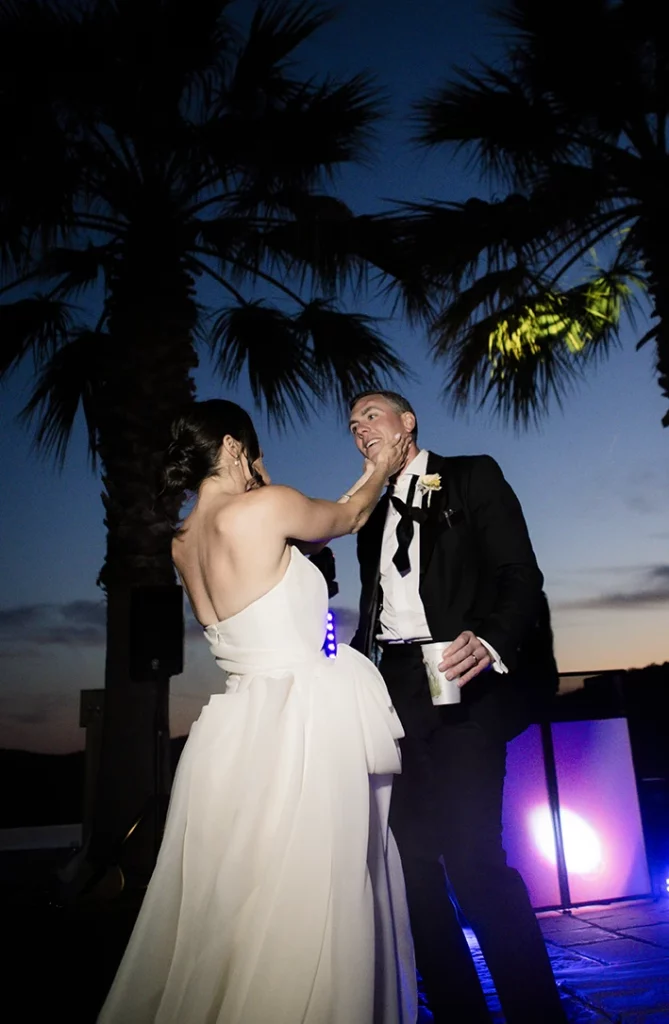 Bride playfully smearing cake on the groom’s face during a wedding celebration in Sitges.