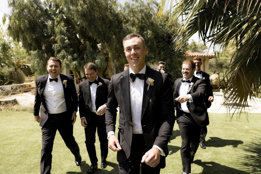 Groom walking with groomsmen in tuxedos during a luxury wedding in Sitges.