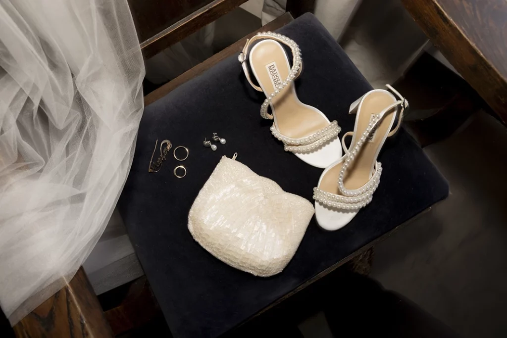 Elegant bridal accessories including white heels, a pearl clutch and jewelry for a luxury wedding in Sitges.