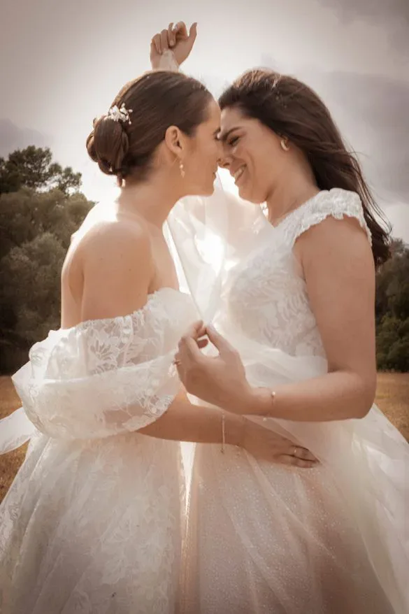 Two brides embracing in a luxurious outdoor wedding, sharing an intimate and exclusive moment, captured with elegance and grace.