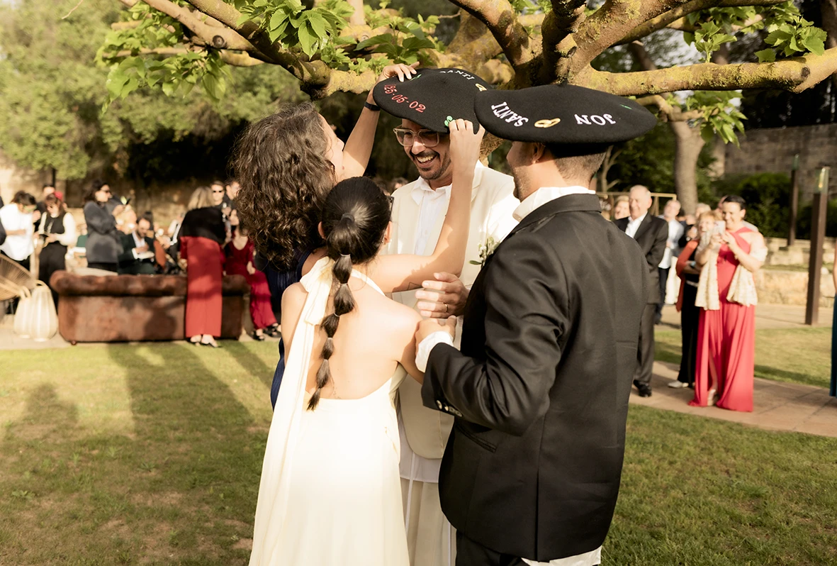 Invitados colocando sombreros a uno de los novios durante la boda en finca Gordiola Mallorca.