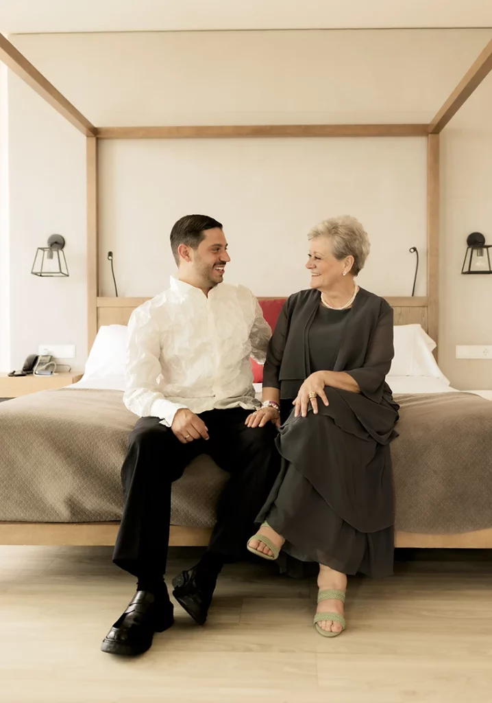 Novio y su madre sonríen sentados en la habitación antes de la boda en finca Gordiola Mallorca.