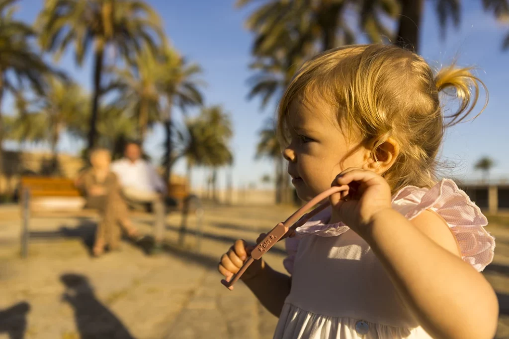 Close-up of a toddler playing with a strap during a family photo session in Palma de Mallorca, with parents blurred in the background.