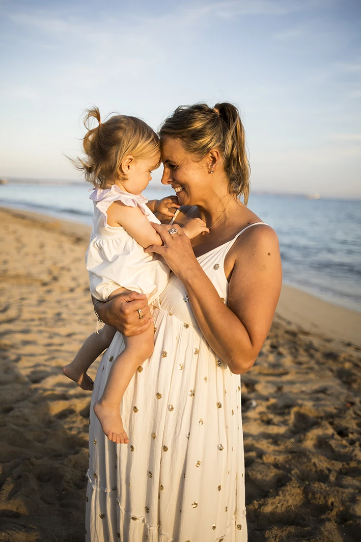 Mother holding her daughter close during a beach photo session in Palma de Mallorca.