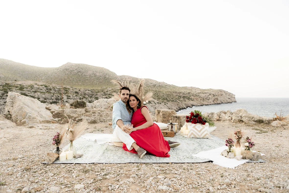 Couple sitting close together on a picnic blanket after a surprise wedding proposal in Mallorca