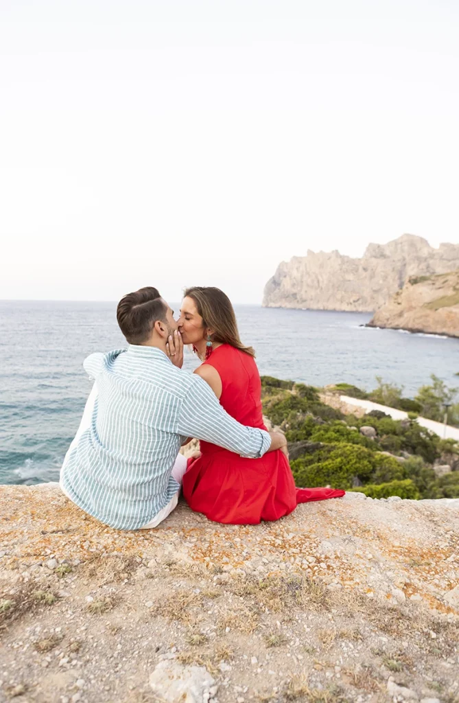 Couple sharing a kiss overlooking the sea during a surprise wedding proposal in Mallorca.
