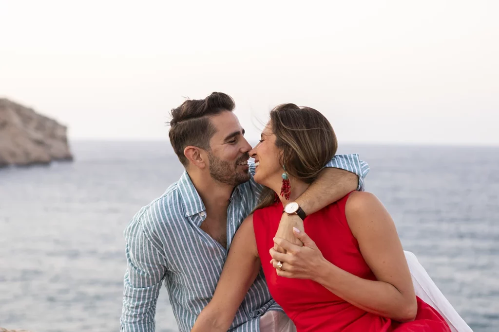 Smiling couple holding hands by the sea after a surprise wedding proposal in Mallorca