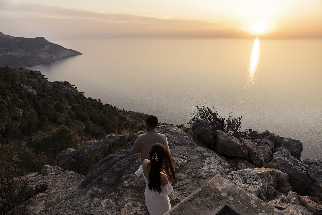 Couple admiring the sea view at sunset after their wedding proposal in Mallorca.
