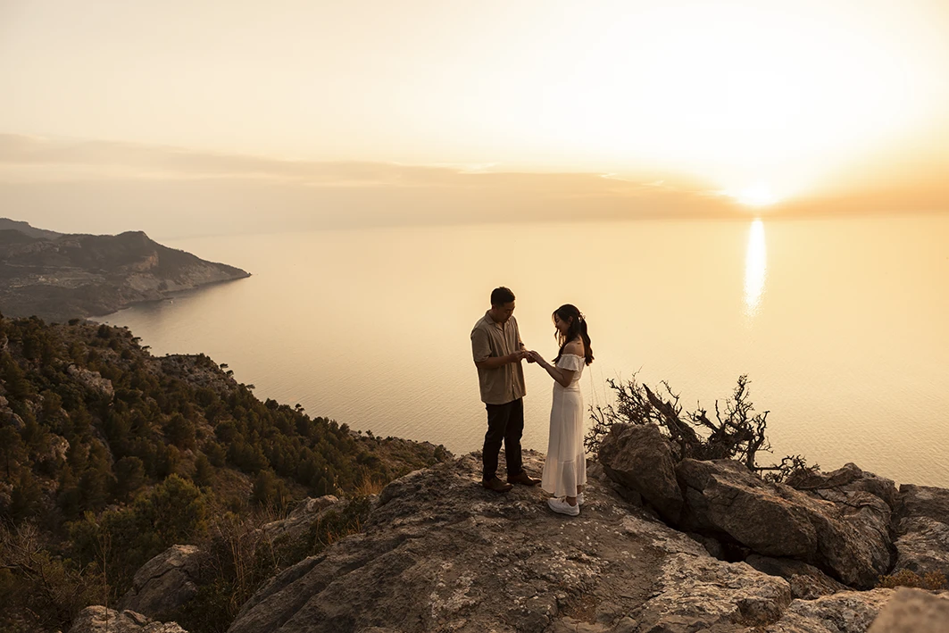 Couple exchanging rings during wedding proposal in Mallorca at sunset.