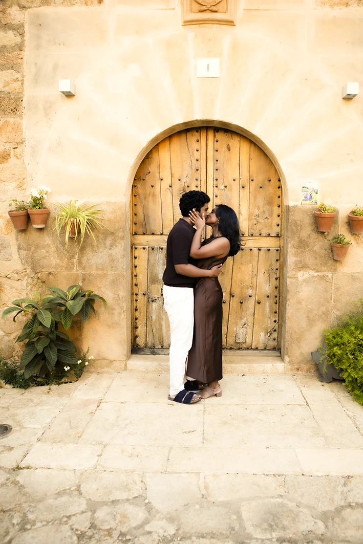 Couple kissing in front of a rustic door after their marriage proposal in Mallorca.