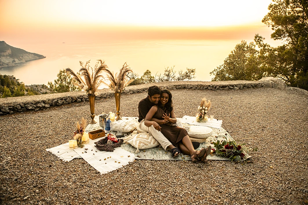 Couple embracing at romantic picnic after marriage proposal in Mallorca.