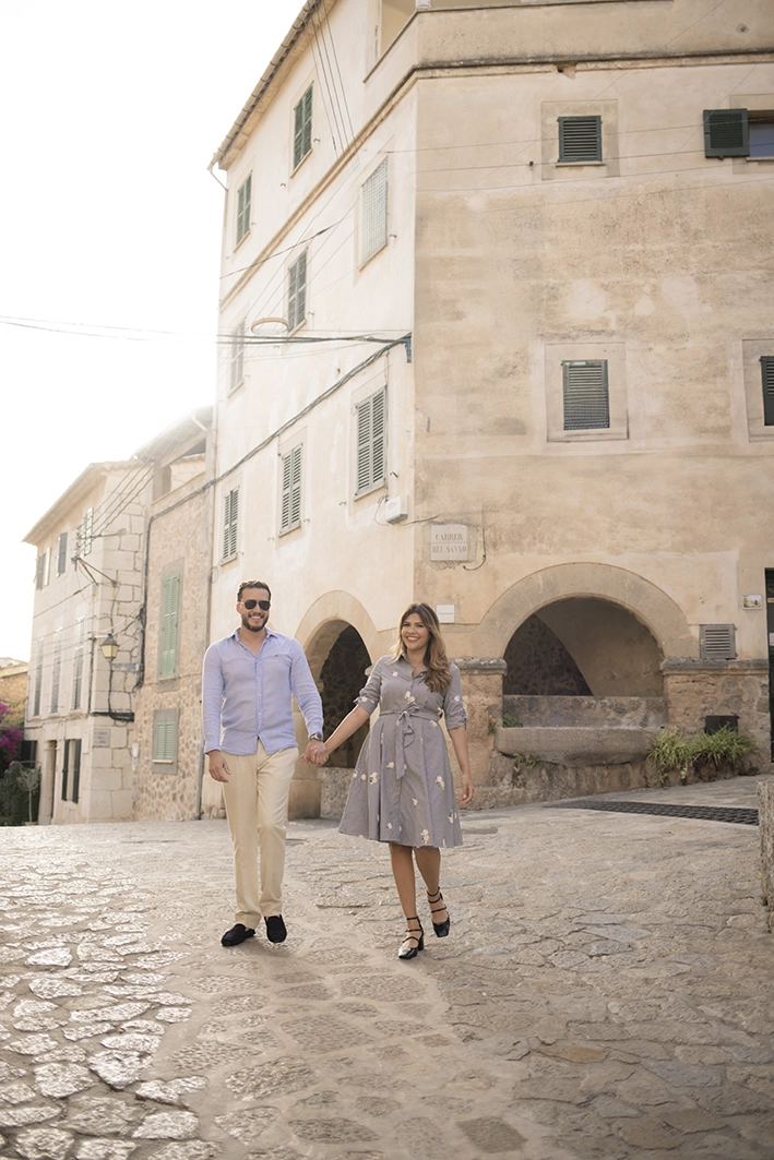 Couple walking hand in hand through a picturesque village in Mallorca before the surprise proposal.