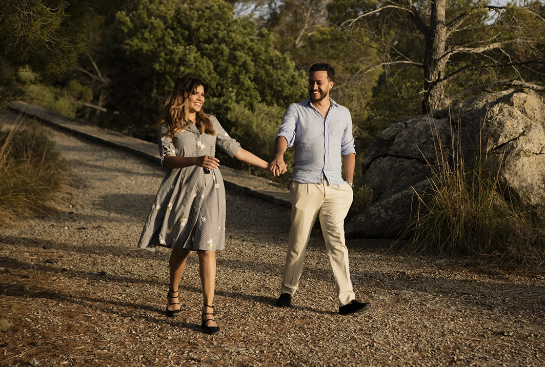 Couple walking happily hand in hand along a natural path in Mallorca before the surprise proposal.