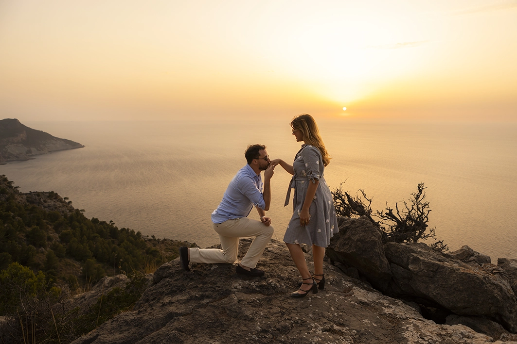 Lucas kissing Rafa’s hand while kneeling during the proposal at sunset in Mallorca.