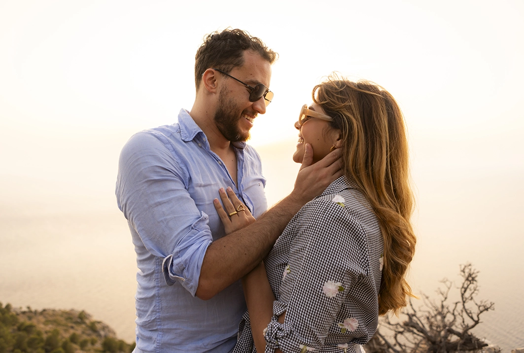 Couple looking at each other tenderly after the proposal on a Mallorca cliff.