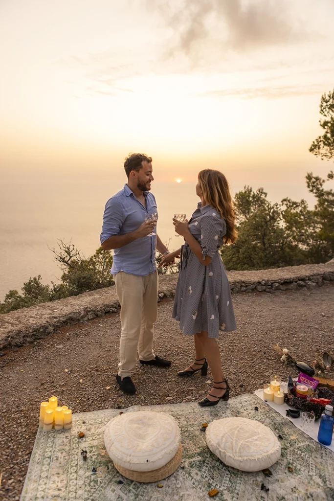 Couple toasting at sunset after their proposal on a Mallorca cliff.