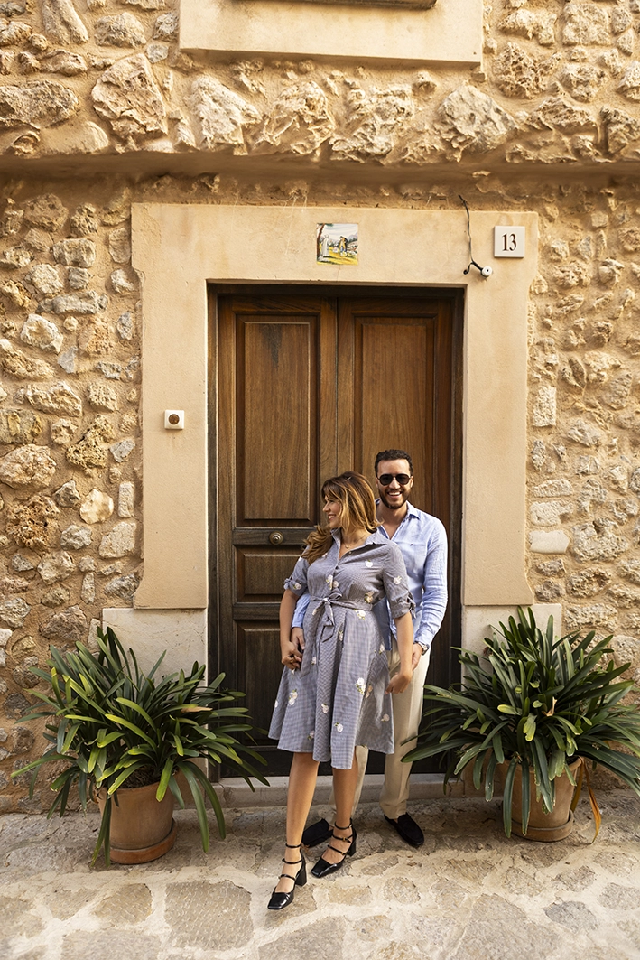 Couple smiling in front of a stone doorway in a traditional Mallorcan village before the proposal.