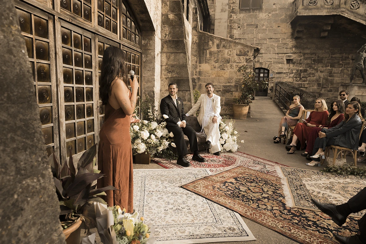 Jon and Santi seated during a heartfelt speech at their wedding at Finca Gordiola.