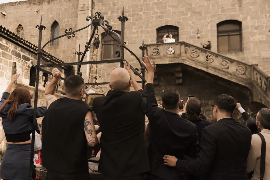 Guests waving and cheering toward the balcony during Jon and Santi’s wedding at Finca Gordiola.