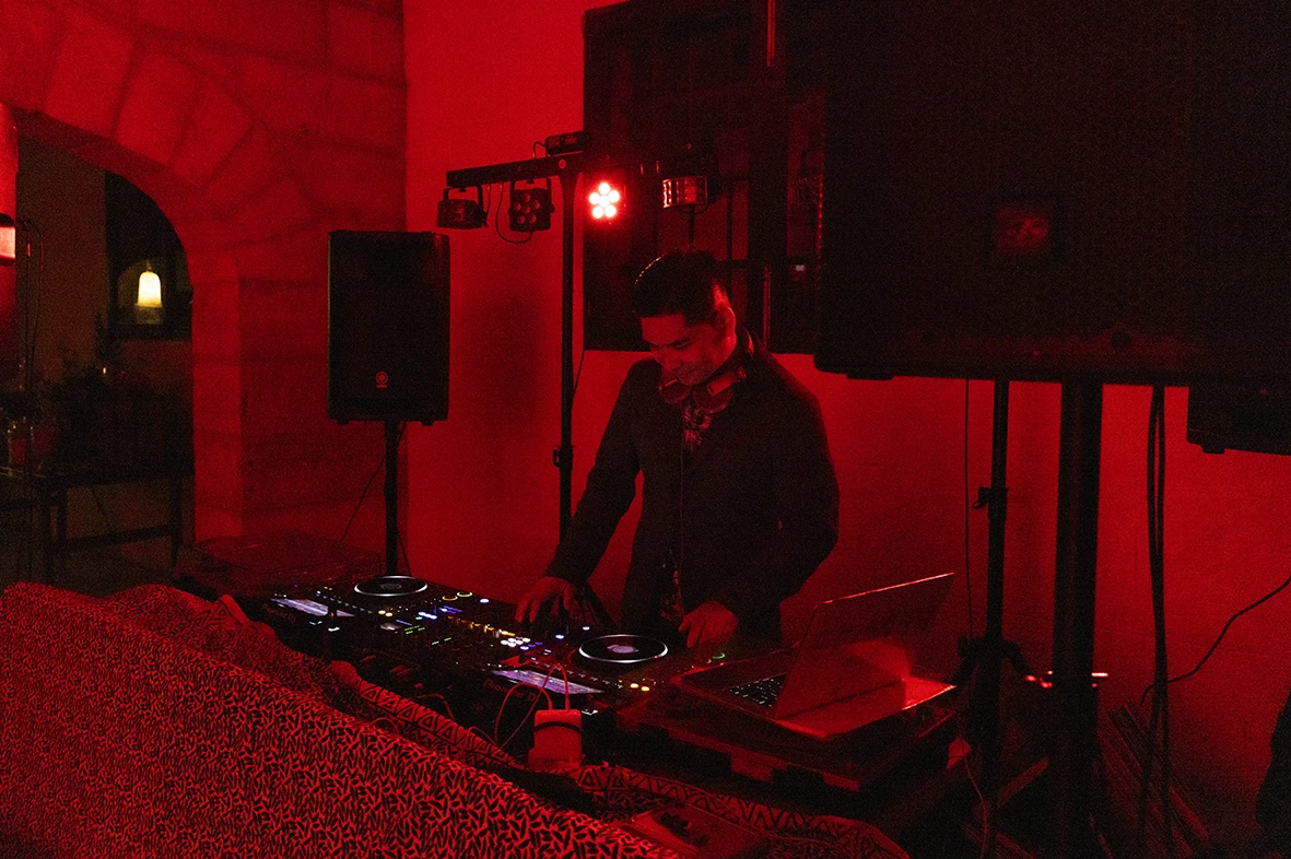 DJ playing music under red lighting during Jon and Santi’s wedding at Finca Gordiola.