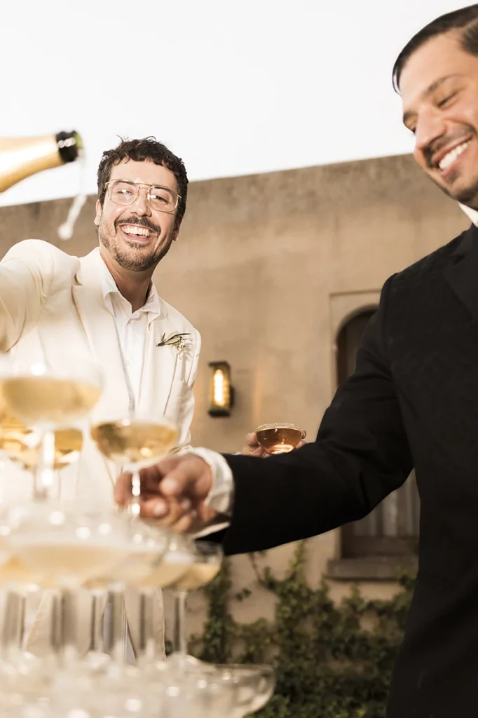 Jon smiling joyfully as champagne is poured into the glass tower at his wedding at Finca Gordiola.