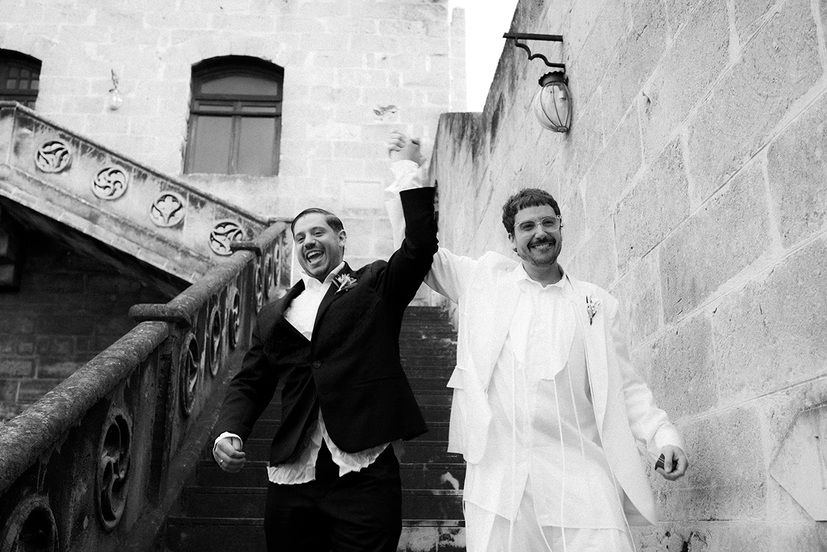 Jon and Santi walking down the stairs with joy at their wedding at Finca Gordiola.