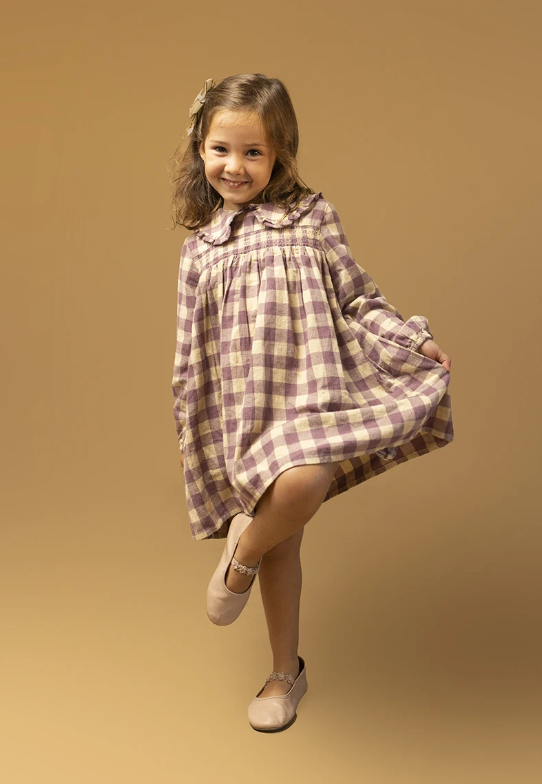 Niña con vestido de cuadros posando. Fotógrafo de niños para agencia en Mallorca.