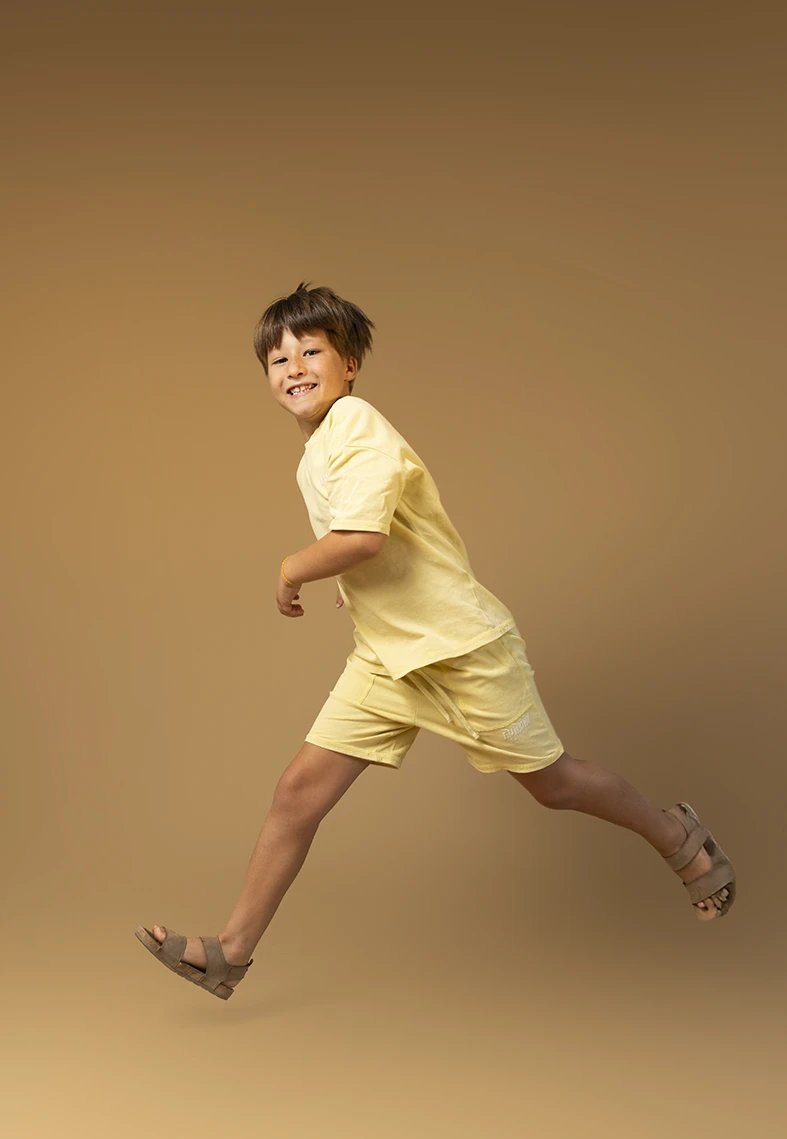 Niño corriendo con ropa amarilla. Fotógrafo de niños para agencia en Mallorca.