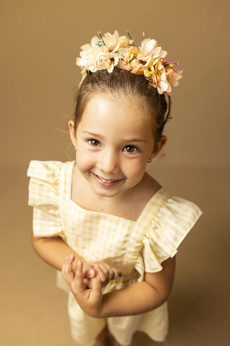 Niña con corona de flores sonriendo. Fotógrafo de niños para agencia en Mallorca.