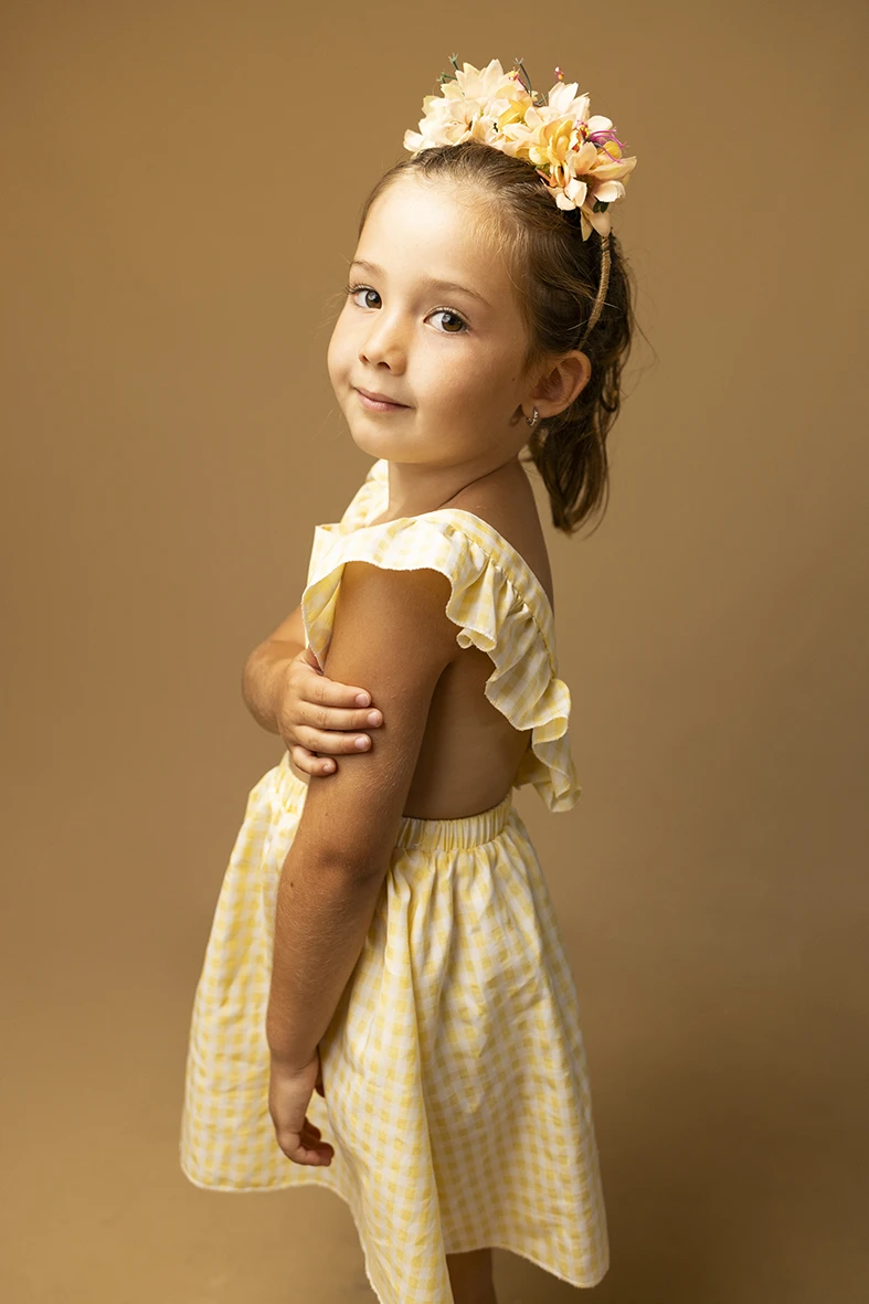 Niña con vestido amarillo de perfil. Fotógrafo de niños para agencia en Mallorca.